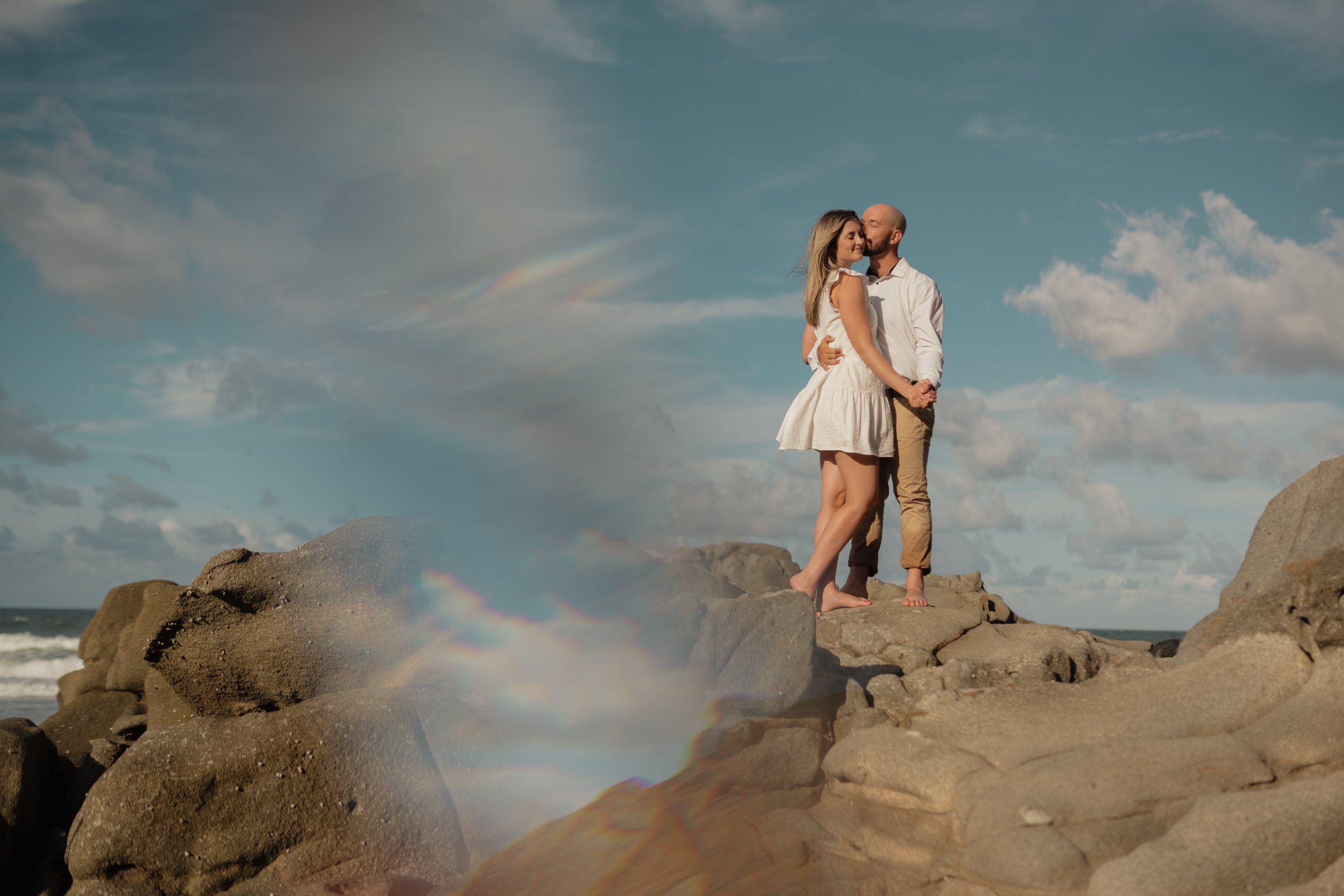 Couple on coastal rocks beneath dramatic sky